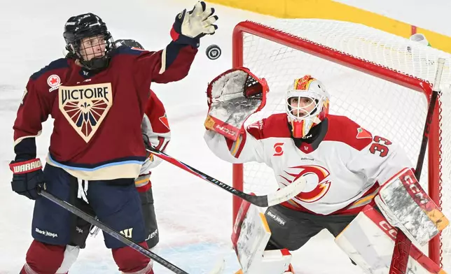 Ottawa Charge goaltender Gwyneth Philips (33) reaches for the puck as Montreal Victoire's Shiann Darkangelo (27) attempts to swat it down during the second period of an PWHL hockey game in Laval, Que., Tuesday, Jan. 13, 2026. (Graham Hughes/The Canadian Press via AP)