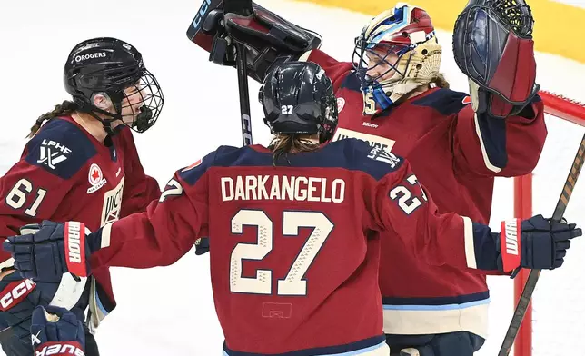Montreal Victoire goaltender Ann-Renee Desbiens (35) celebrates with teammates Nicole Gosling (61) and Shiann Darkangelo (27) after defeating the Ottawa Charge in a PWHL hockey game in Laval, Que., Tuesday, Jan. 13, 2026. (Graham Hughes/The Canadian Press via AP)