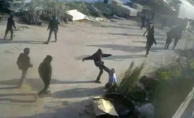 This frame grab from security camera footage filmed Jan. 8, 2026, and obtained by The Associated Press, shows men dressed mostly in black with their faces covered, one of whom is kicking a man on the ground as he tried to flee a nursery in the northern West Bank village of Deir Sharaf. Two people who witnessed the attack and are members of the family that owns the facility said the assailants were Israeli settlers beating 67-year-old Basim Saleh Yassin.(UGC via AP)