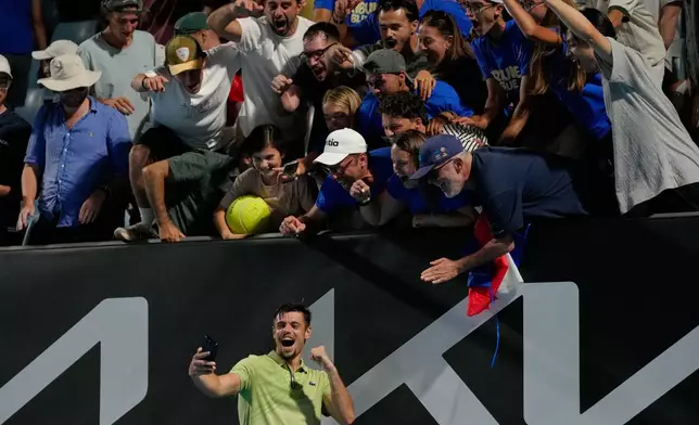 Arthur Gea of France takes a selfie with supporters after defeating Jiri Lehecka of the Czech Republic in their first round match at the Australian Open tennis championship in Melbourne, Australia, Monday, Jan. 19, 2026. (AP Photo/Dar Yasin)