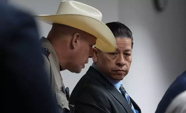 Former Uvalde school district police officer Adrian Gonzales, right, talks with an officer as he arrives in the courtroom at the Nueces County Courthouse in Corpus Christi, Texas, Tuesday, Jan. 6, 2026. (AP Photo/Eric Gay, Pool)
