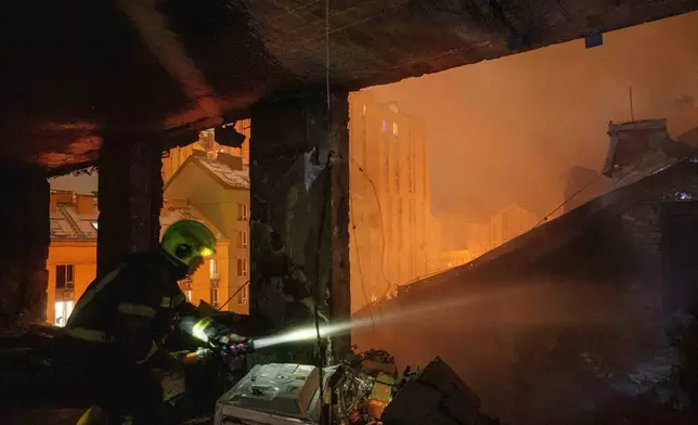 A rescue worker put out fire of a residential building damaged by a Russian strike on Kyiv, Ukraine, on Friday, Jan. 9, 2026. (AP Photo/Evgeniy Maloletka)