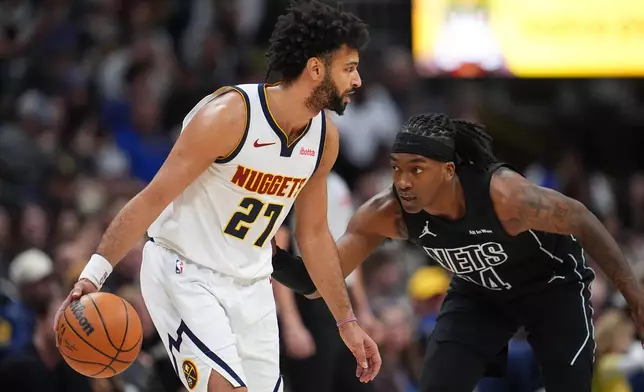 Denver Nuggets guard Jamal Murray, left, looks to drive to the rim as Brooklyn Nets guard Terance Mann defends in the first half of an NBA basketball game, Thursday, Jan. 29, 2026, in Denver. (AP Photo/David Zalubowski)