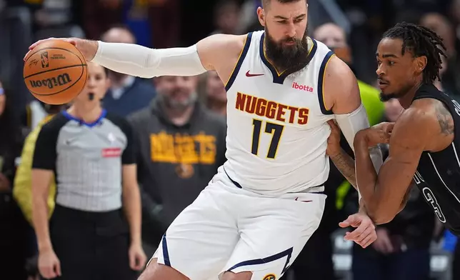 Denver Nuggets center Jonas Valančiūnas (17) drives to the net as Brooklyn Nets center Nic Claxton, right, defends in the first half of an NBA basketball game Thursday, Jan. 29, 2026, in Denver. (AP Photo/David Zalubowski)