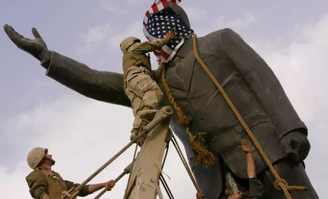FILE - Cpl. Edward Chin of the 3rd Battalion, 4th Marines Regiment, covers the face of a statue of Saddam Hussein with an American flag before toppling the statue in downtown Baghdad, Iraq, on April 9, 2003. (AP Photo/Jerome Delay, File)