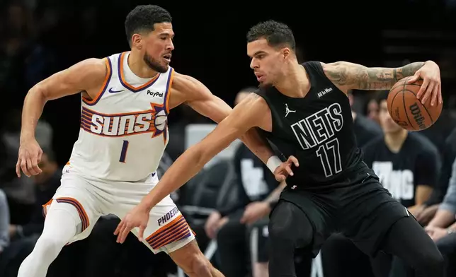 Phoenix Suns' Devin Booker (1) defends Brooklyn Nets' Michael Porter Jr. (17) during the first half of an NBA basketball game Monday, Jan. 19, 2026, in New York. (AP Photo/Frank Franklin II)