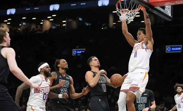 Phoenix Suns' Oso Ighodaro (11) dunks the ball in front of Brooklyn Nets' Michael Porter Jr. (17) during the first half of an NBA basketball game Monday, Jan. 19, 2026, in New York. (AP Photo/Frank Franklin II)