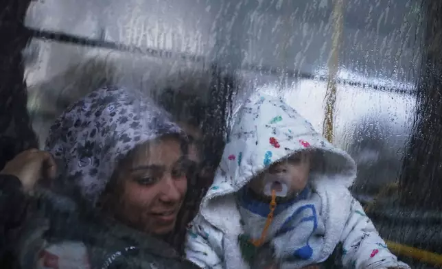Displaced residents look out from a bus window as they return to the Achrafieh neighborhood after days of fighting between government forces and Kurdish fighters in the northern city of Aleppo, Syria, Monday, Jan. 12, 2026. (AP Photo/Omar Albam)