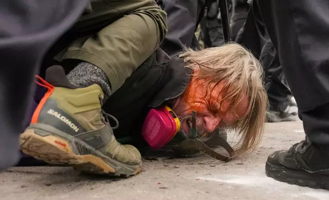 A man is pushed to the ground as federal immigration officers confront protesters outside Bishop Henry Whipple Federal Building, Thursday, Jan. 15, 2026, in Minneapolis. (AP Photo/John Locher)