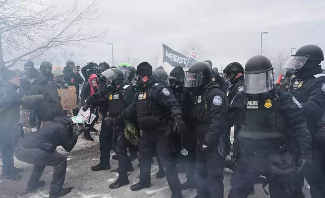 Federal immigration officers confront protesters outside Bishop Henry Whipple Federal Building, Thursday, Jan. 15, 2026, in Minneapolis. (AP Photo/Adam Gray)