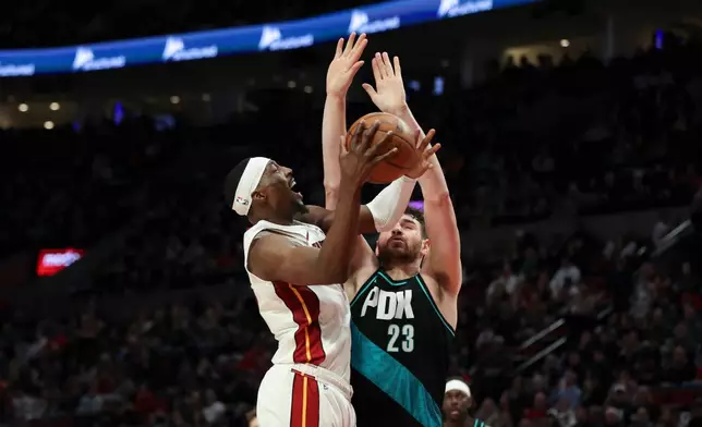 Miami Heat center Bam Adebayo, left, drives to the basket as Portland Trail Blazers center Donovan Clingan (23) defends during the first half of an NBA basketball game Thursday, Jan. 22, 2026, in Portland, Ore. (AP Photo/Amanda Loman)