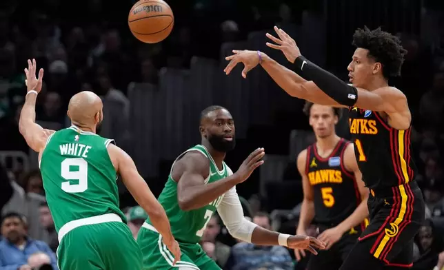 Atlanta Hawks forward Jalen Johnson (1) passes over Boston Celtics guard Derrick White (9) during the first half of an NBA basketball game, Wednesday, Jan. 28, 2026, in Boston. (AP Photo/Robert F. Bukaty)