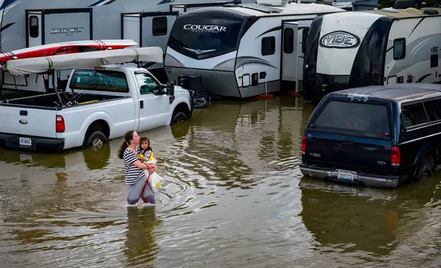 People wade through an rv park flooded by the "King Tides", occurring when the sun, moon and Earth align, causing a stronger gravitational pull Saturday, Jan. 3, 2026, near Corte Madera in Marin County, Calif. (AP Photo/Ethan Swope)