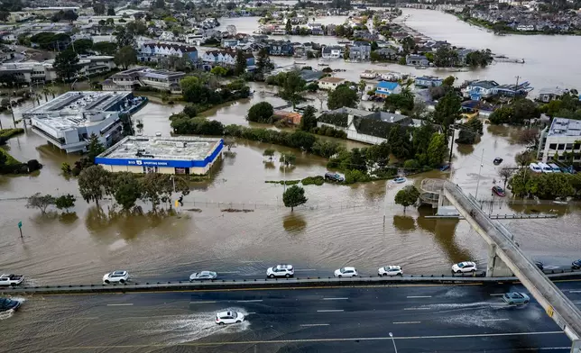 Cars drive on highway 101 flooded by the "King Tides", occurring when the sun, moon and Earth align, causing a stronger gravitational pull Saturday, Jan. 3, 2026, near Corte Madera in Marin County, Calif. (AP Photo/Ethan Swope)