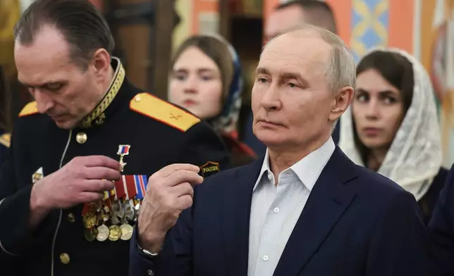 Russian President Vladimir Putin, right, accompanied by military personnel and their families, crosses himself during the Orthodox Christmas service at the Church of Great-Martyr St. George the Victorious in Solnechnogorsk-2, outside Moscow, on Wednesday, Jan. 7, 2026. (Vyacheslav Prokofyev, Sputnik, Kremlin Pool Photo via AP)