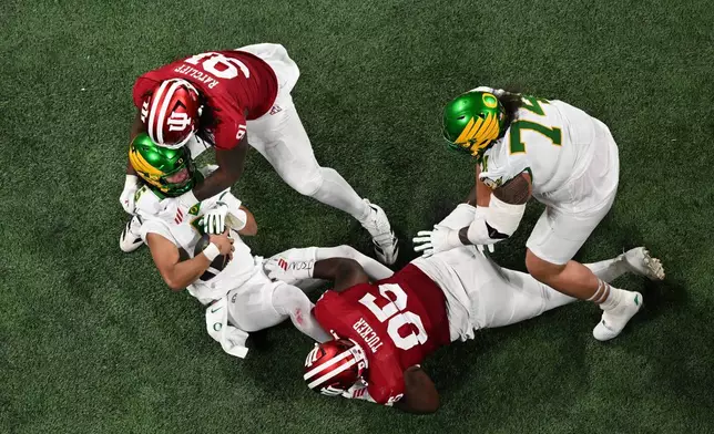 Oregon quarterback Dante Moore (5) is sacked by Indiana defensive lineman Dominique Ratcliff (91) during the first half of the Peach Bowl NCAA college football playoff semifinal, Friday, Jan. 9, 2026, in Atlanta. (AP Photo/Danny Karnik)