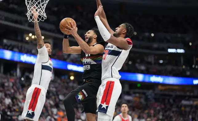 Denver Nuggets guard Jamal Murray, center, drives to the basket between Washington Wizards guard Justin Champagnie, left, and center Alex Sarr, front right, in the second half of an NBA basketball game Saturday, Jan. 17, 2026, in Denver. (AP Photo/David Zalubowski)