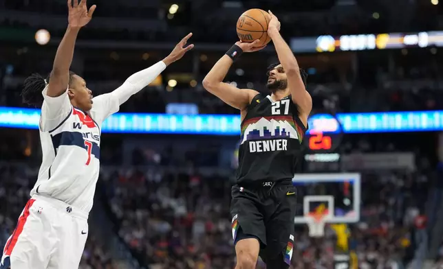 Denver Nuggets guard Jamal Murray, right, looks to shoot for a basket over Washington Wizards guard Bub Carrington, left, in the second half of an NBA basketball game Saturday, Jan. 17, 2026, in Denver. (AP Photo/David Zalubowski)
