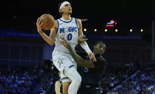 Orlando Magic guard Anthony Black (0) collides with Memphis Grizzlies guard Vince Williams Jr. (5) during the first half of NBA basketball game Sunday, Jan. 18, 2026, in London. (AP Photo/Kin Cheung)
