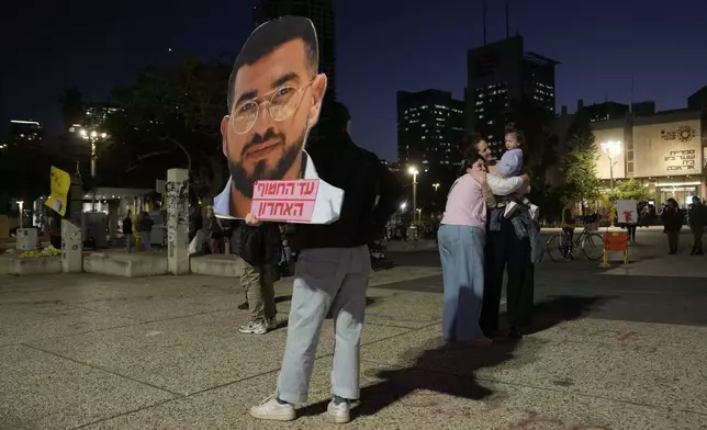 A woman carries a photo of Israeli hostage Ran Gvili after the announcement that his remains were the last to be recovered from Gaza, had been identified, in a plaza known as Hostages Square in Tel Aviv, Israel, Monday, Jan. 26, 2026. (AP Photo/Oded Balilty)