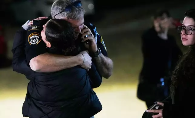 A police officer hugs a family member of Israeli hostage Ran Gvili after the announcement that his remains were the last to be recovered from Gaza, at his home in the village of Meitar, southern Israel, Monday, Jan. 26, 2026. (AP Photo/Ohad Zwigenberg)