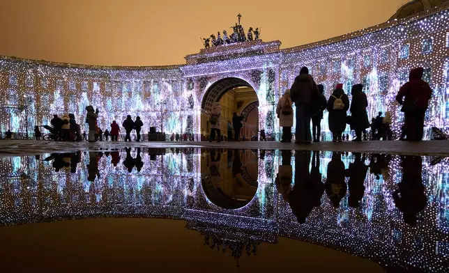 FILE - People watch a multimedia light show during the "Country of Light" festival at the Palace Square in St. Petersburg, Russia, Dec. 7, 2025. (AP Photo/Dmitri Lovetsky, File)