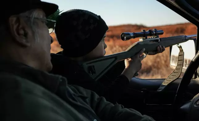 FILE - Roswell Schaeffer, an Inupiaq hunter and fisher, helps his 7-year-old great-grandson James Schaeffer scope ducks while hunting in Kotzebue, Alaska, Sept. 26, 2025. (AP Photo/Annika Hammerschlag, File)
