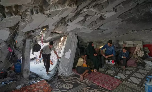 FILE - Sahar Taroush speaks with her brother after returning to her collapsed home in Jabaliya, Gaza City, Nov. 11, 2025, following the latest ceasefire. Her children are Ammar, far left, Hassan sitting with with his 2-year-old sister Ahlam, and Bisan, right. (AP Photo/Jehad Alshrafi, File)