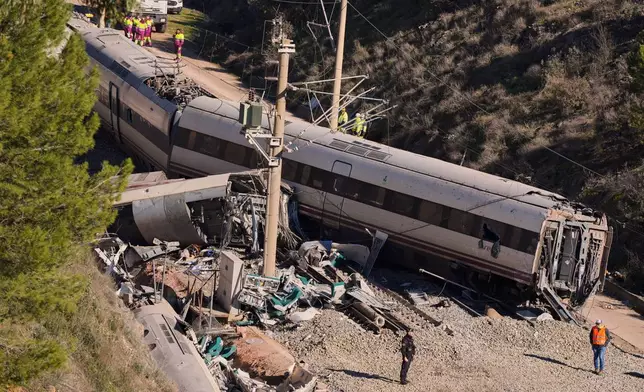 Guardia Civil officers collect evidence next to the wreckage of train cars involved in a collision in Adamuz, southern Spain, Tuesday, Jan. 20, 2026. (AP Photo/Manu Fernandez)