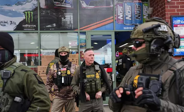 U.S. Border Patrol Cmdr. Gregory Bovino, center, and other federal immigration officers stop at a gas station Tuesday, Jan. 13, 2026, in Columbia Heights, Minn. (AP Photo/Adam Gray)