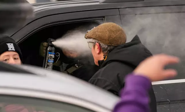 A federal immigration officer deploys pepper spray as officers make an arrest Sunday, Jan. 11, 2026, in Minneapolis. (AP Photo/John Locher)