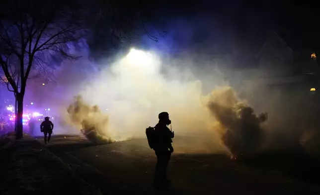 Law enforcement officers stand amid tear gas at the scene of a reported shooting Wednesday, Jan. 14, 2026, in Minneapolis. (AP Photo/Adam Gray)