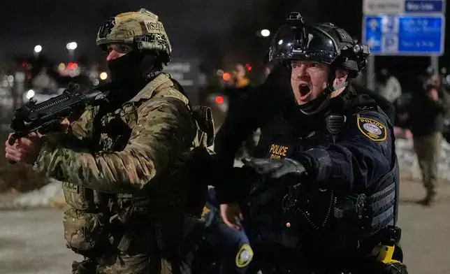 Federal immigration officers confront protesters outside Bishop Henry Whipple Federal Building, Thursday, Jan. 15, 2026, in Minneapolis. (AP Photo/Yuki Iwamura)