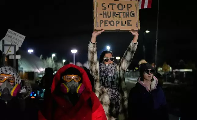 A woman holds up a sign as federal immigration officers confront protesters outside Bishop Henry Whipple Federal Building, Thursday, Jan. 15, 2026, in Minneapolis. (AP Photo/Yuki Iwamura)