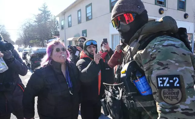 People confront a U.S. Border Patrol officer Wednesday, Jan. 14, 2026, in Minneapolis. (AP Photo/Adam Gray)