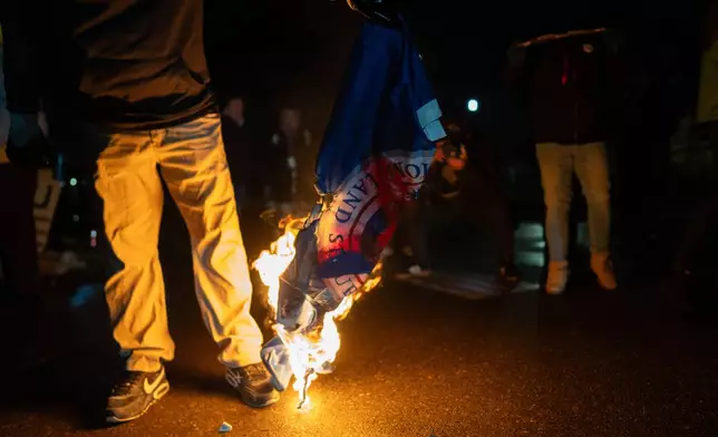 A protester burns the flag of the United States Department of Homeland Security outside the Bishop Henry Whipple Federal Building, Tuesday, Jan. 13, 2026, in Minneapolis. (AP Photo/Adam Gray)