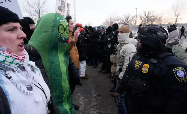 A person wearing a Pickle Rick costume stands against federal law enforcement during a protest outside the Bishop Henry Whipple Federal Building on Saturday, Jan. 17, 2026, in Minneapolis. (AP Photo/Yuki Iwamura)