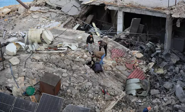 People look through the rubble of a destroyed building that was hit by an Israeli airstrike at a commercial district in the southern port city of Sidon, Lebanon, Tuesday, Jan. 6, 2026. (AP Photo/Mohammed Zaatari)