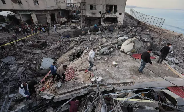 People check a destroyed building that was hit by an Israeli airstrike at a commercial district, in the southern port city of Sidon, Lebanon, Tuesday, Jan. 6, 2026. (AP Photo/Mohammed Zaatari)