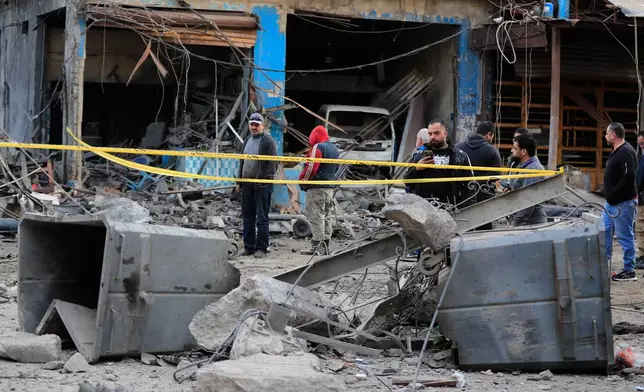People check the site where an Israeli strike destroyed a building at a commercial district in the southern port city of Sidon, Lebanon, Tuesday, Jan. 6, 2026. (AP Photo/Mohammed Zaatari)