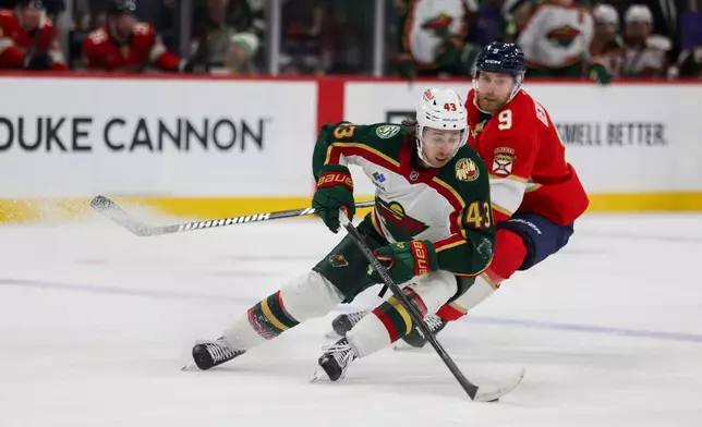 Minnesota Wild's Quinn Hughes (43) controls the puck with Florida Panthers' Sam Bennett (9) right behind him during the second period of an NHL hockey game, Saturday, Jan. 24, 2026, in St. Paul, Minn. (AP Photo/Lily Dozier)