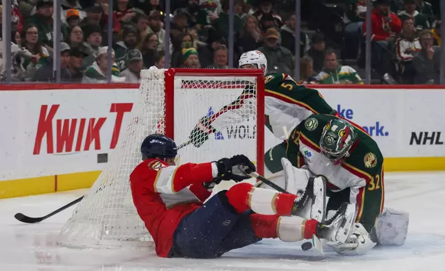 Florida Panthers' Sam Bennett, left, trips over Minnesota Wild goalie Filip Gustavsson (32) during the first period of an NHL hockey game, Saturday, Jan. 24, 2026, in St. Paul, Minn. (AP Photo/Lily Dozier)