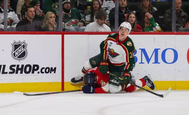 Minnesota Wild's Danila Yurov (22) and Florida Panthers' A.J. Greer (10) fall over each other during the second period of an NHL hockey game, Saturday, Jan. 24, 2026, in St. Paul, Minn. (AP Photo/Lily Dozier)