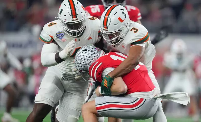 Ohio State quarterback Julian Sayin, center, is sacked by Miami defensive lineman Rueben Bain Jr., left, and defensive lineman Akheem Mesidor during the first half of the Cotton Bowl College Football Playoff quarterfinal game Wednesday, Dec. 31, 2025, in Arlington, Texas. (AP Photo/Julio Cortez)