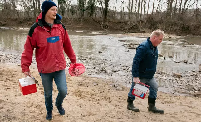 Potomac River Keeper Dean Naujoks, right, and volunteer water quality River Keeper Evan Quinter, carry coolers containing samples of river water which will be checked for Ecoli, alongside the site where a massive pipe rupture has sent sewage spilling into the Potomac River, in Glen Echo, Md., Friday, Jan. 23, 2026. (AP Photo/Cliff Owen)