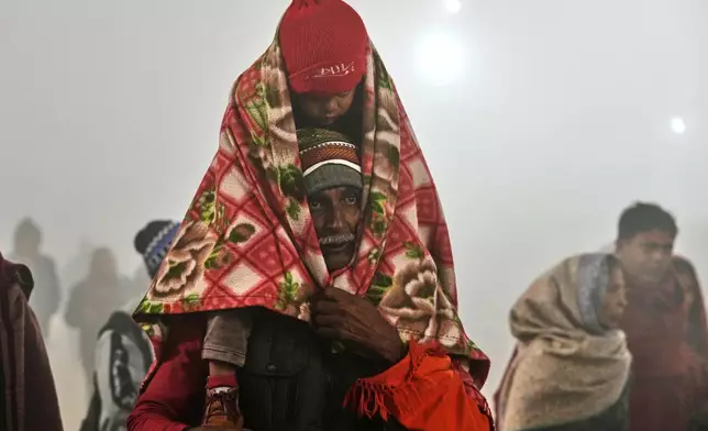 Devotees arrive for a holy dip on Mauni Amavasya, a divine occasion in Hindu religious practice followed for honoring ancestors or forefathers, at the Sangam, the confluence of the Ganges, the Yamuna and the mythical Saraswati rivers, during the annual month long Hindu religious fair "Magh Mela" in Prayagraj, India, Sunday, Jan. 18, 2026. (AP Photo/Rajesh Kumar Singh)