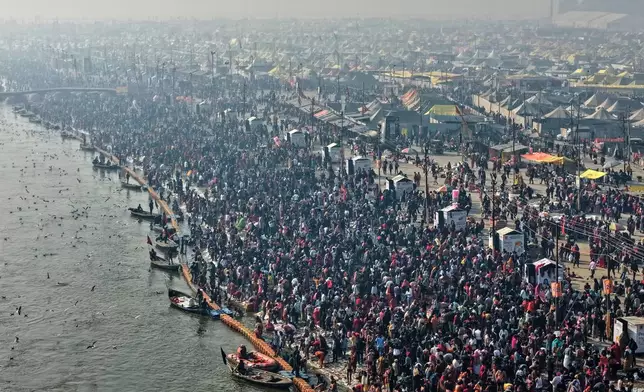 Devotees arrive for a holy dip on Mauni Amavasya, a divine occasion in Hindu religious practice followed for honoring ancestors or forefathers, at the Sangam, the confluence of the Ganges, the Yamuna and the mythical Saraswati rivers, during the annual month long Hindu religious fair "Magh Mela" in Prayagraj, India, Sunday, Jan. 18, 2026. (AP Photo/Rajesh Kumar Singh)