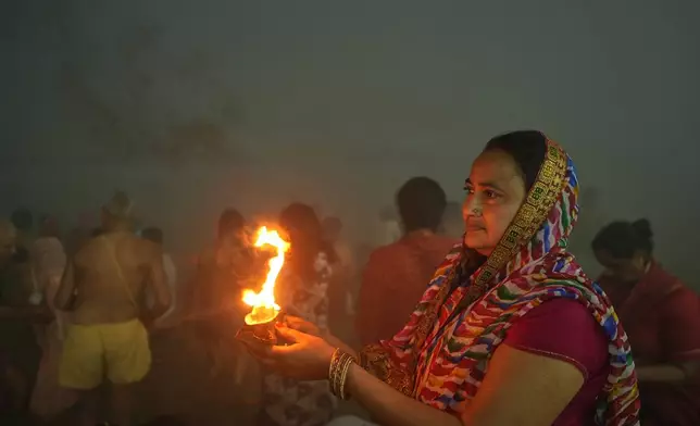 Devotees pray after holy dip on Mauni Amavasya, a divine occasion in Hindu religious practice followed for honoring ancestors or forefathers, at the Sangam, the confluence of the Ganges, the Yamuna and the mythical Saraswati rivers, during the annual month long Hindu religious fair "Magh Mela" in Prayagraj, India, Sunday, Jan. 18, 2026. (AP Photo/Rajesh Kumar Singh)