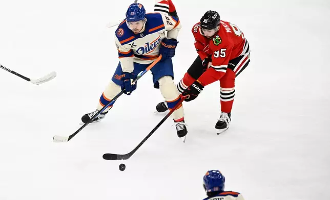 Chicago Blackhawks right wing Ilya Mikheyev (95) moves the puck against Edmonton Oilers center Jack Roslovic (28) during the second period of an NHL hockey game, Monday, Jan. 12, 2026, in Chicago. (AP Photo/Matt Marton)