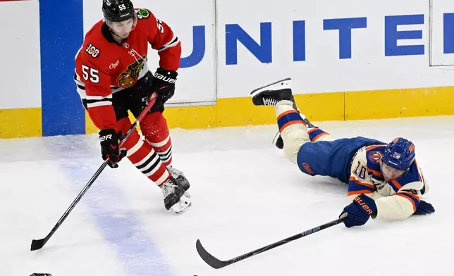 Edmonton Oilers center Curtis Lazar, right, flips the puck past Chicago Blackhawks defenseman Artyom Levshunov (55) during the second period of an NHL hockey game, Monday, Jan. 12, 2026, in Chicago. (AP Photo/Matt Marton)